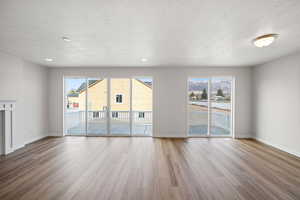 Unfurnished living room featuring a textured ceiling and light hardwood / wood-style floors