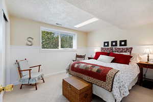 Bedroom with a textured ceiling and light colored carpet