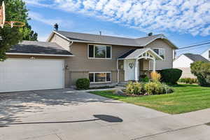 Bi-level home featuring a garage and a front yard