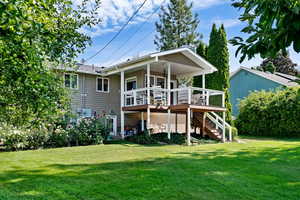 Rear view of house with a yard and a wooden deck