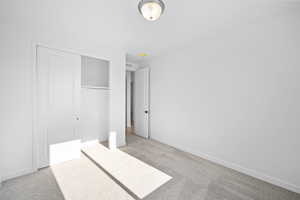 Unfurnished bedroom featuring light colored carpet and a closet