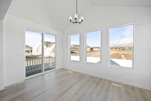 Interior space with light hardwood / wood-style floors, an inviting chandelier, and lofted ceiling