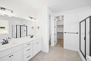 Bathroom with tile patterned flooring, a shower with door, vanity, and toilet