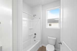 Bathroom with hardwood / wood-style floors, shower / bath combination, and toilet