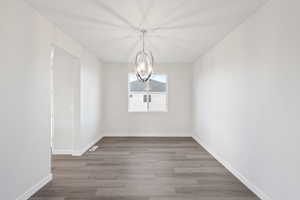 Unfurnished dining area featuring hardwood / wood-style flooring and an inviting chandelier