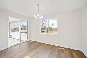 Unfurnished dining area featuring light wood-type flooring and a chandelier