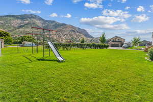 View of yard with a garage, a mountain view, and a playground