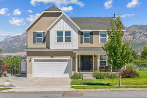 View of front of house featuring a front lawn, a mountain view, and a garage