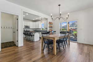 Dining area featuring sink, an inviting chandelier, and dark hardwood / wood-style flooring