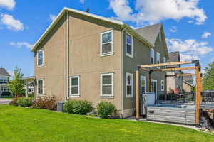 Rear view of house featuring a pergola, central AC, and a yard