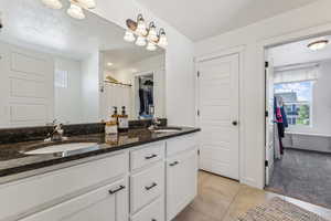 Bathroom featuring double sink vanity, a textured ceiling, and tile patterned flooring