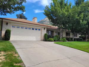 Ranch-style house featuring a front lawn and a garage