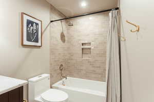 Full bathroom featuring toilet, shower / tub combo with curtain, and vanity