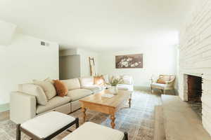 Living room with light wood-type flooring and a stone fireplace