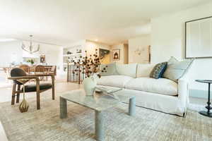 Living room with built in shelves, light hardwood / wood-style flooring, and an inviting chandelier