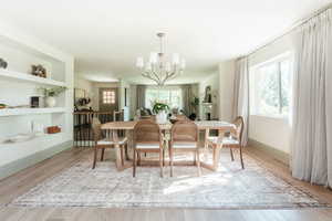 Dining area with built in shelves, a notable chandelier, and light wood-type flooring