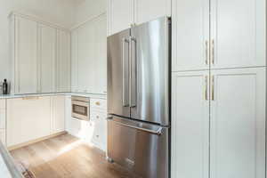 Kitchen with light wood-type flooring, stainless steel appliances, and white cabinetry