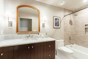 Full bathroom featuring tiled shower / bath combo, vanity, and toilet