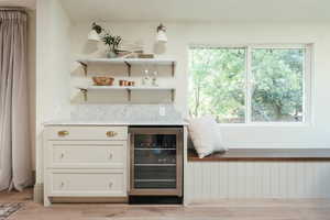 Bar featuring beverage cooler, white cabinets, and light wood-type flooring