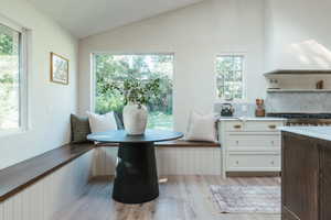 Dining room with light hardwood / wood-style flooring, vaulted ceiling, and a healthy amount of sunlight