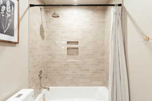 Bathroom featuring toilet and shower / tub combo with curtain