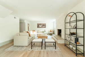 Living room featuring light hardwood / wood-style flooring and a stone fireplace