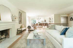 Living room featuring light wood-type flooring, a premium fireplace, built in features, and a chandelier