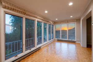 Sunroom with electric baseboard and floor to ceiling windows showcasing beautiful sunset