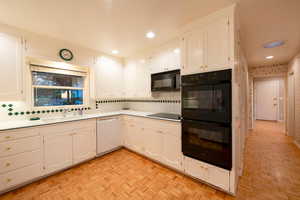 Kitchen with decorative backsplash, light parquet flooring, double oven, and white cabinetry