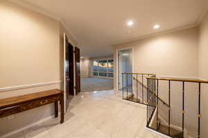 Hallway featuring light floors and crown molding