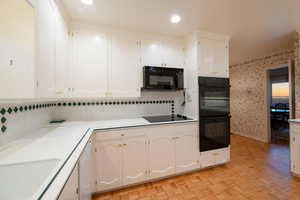 Kitchen featuring white cabinets, light parquet flooring, decorative backsplash, and double oven