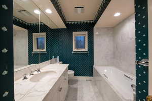 Full bathroom in primary suite, marble surfaces