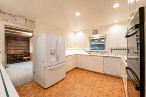 Kitchen featuring decorative backsplash, white cabinetry, sink, light parquet floors, and white appliances