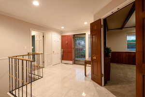 Hallway with light floors and ornamental molding, leading into office