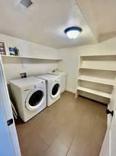 Laundry room featuring sink, washing machine and clothes dryer, a textured ceiling, and cabinets