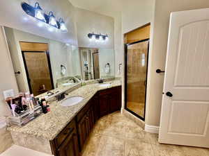 Bathroom with double vanity, walk in shower, and tile patterned flooring