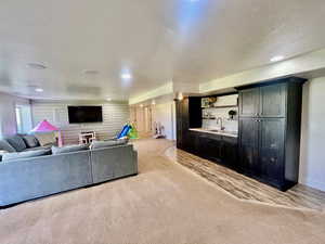 Living room with light colored carpet, a textured ceiling, and sink