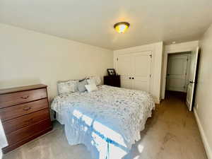 Bedroom with a textured ceiling, a closet, and light carpet