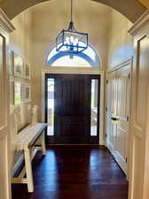 Foyer with a towering ceiling, an inviting chandelier, and wood-type flooring