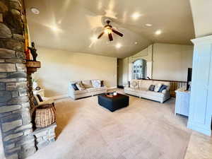 Carpeted living room featuring ceiling fan and vaulted ceiling