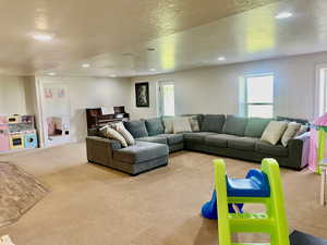 Living room with a wealth of natural light, light colored carpet, and a textured ceiling