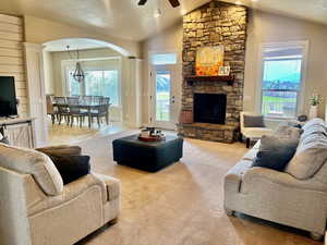 Living room featuring ceiling fan, light carpet, a textured ceiling, and lofted ceiling