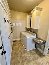 Laundry area featuring washing machine and dryer, light tile patterned floors, and cabinets