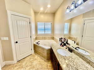 Bathroom featuring tiled bath, tile patterned flooring, and vanity