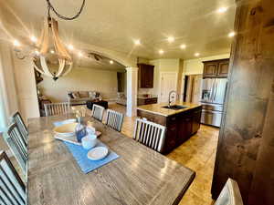 Dining room with light tile patterned flooring, sink, decorative columns, and a textured ceiling