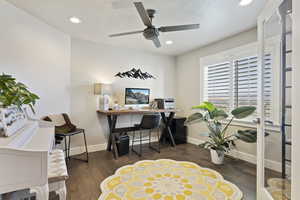 Home office with ceiling fan and dark hardwood / wood-style floors