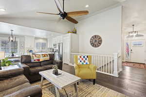 Living room featuring sink, high vaulted ceiling, ceiling fan with notable chandelier, and wood-type flooring