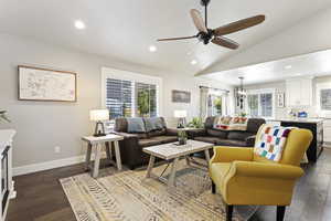 Living room featuring ceiling fan with notable chandelier, lofted ceiling, and wood-type flooring