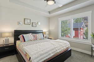 Bedroom featuring carpet, a raised ceiling, and ceiling fan