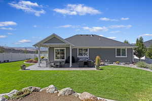 Back of house with a lawn, an outdoor living space, and a patio area